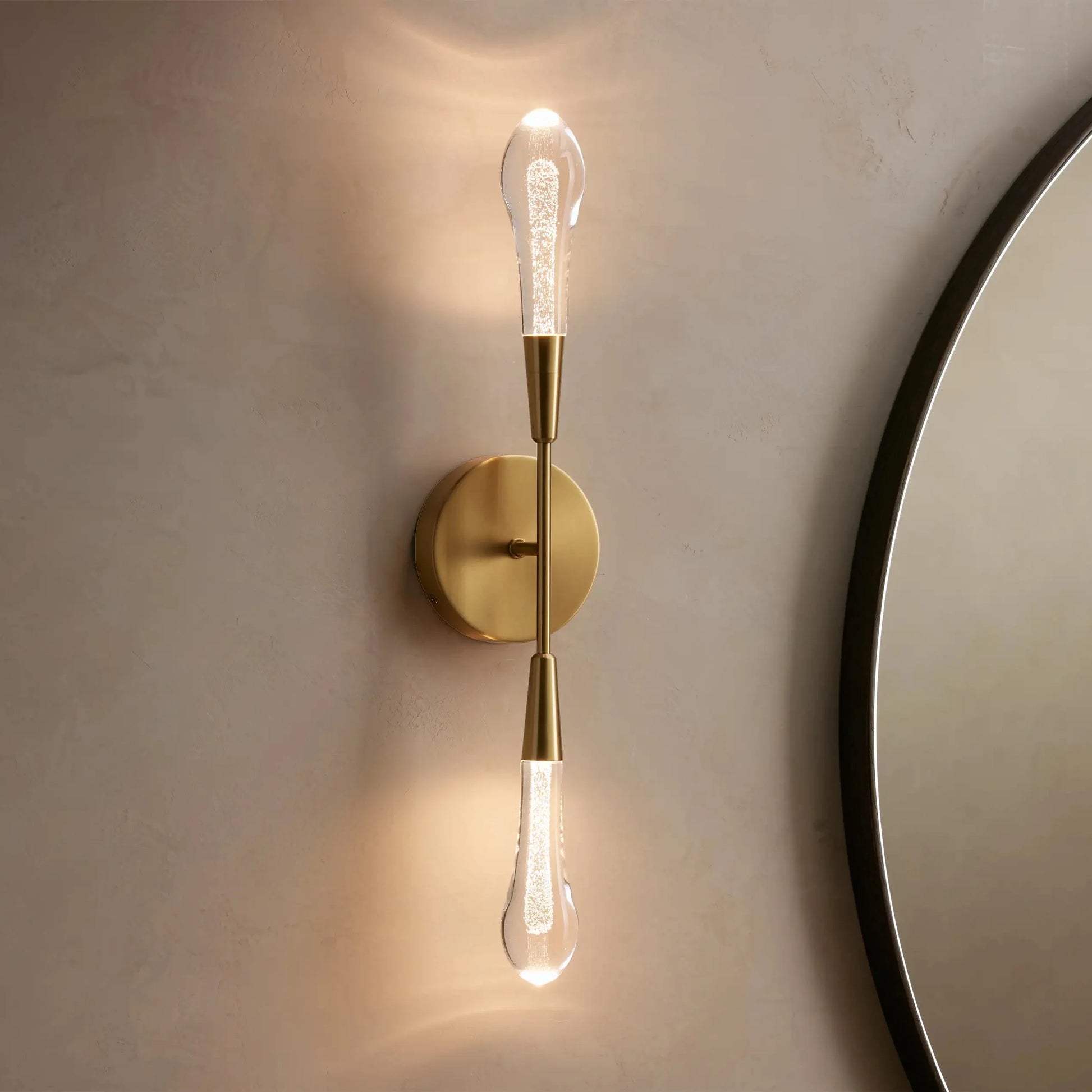 Gold wall sconce with a round mirror on a beige wall